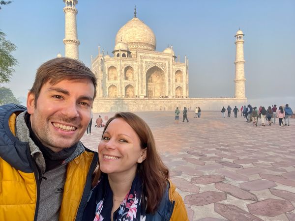 Matt & Jade smile at the camera with the Taj Mahal behind them.